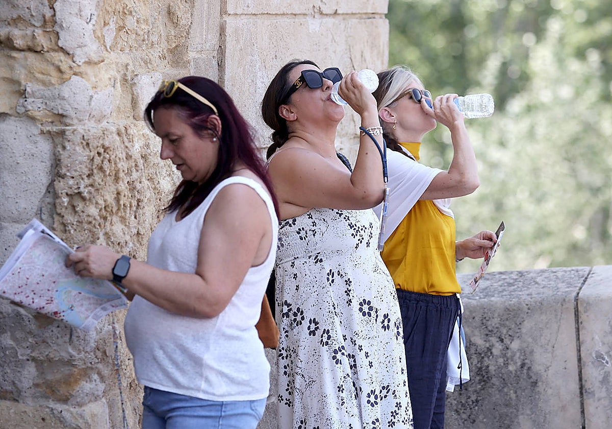 Varias mujeres beben agua este domingo a la sombra en el puente Romano