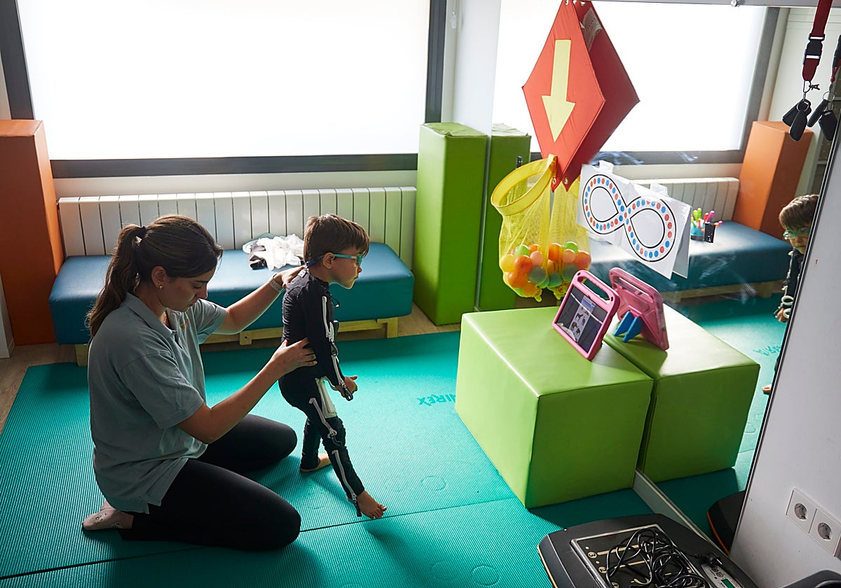 Roma, con tres años, sufre del síndrome CDG. Carmen, su fisioterapeuta, practica con él ejercicios motores a diario