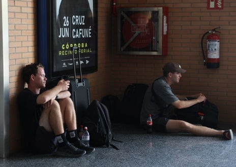 Imagen secundaria 1 - Arriba, viajeros miran las salidas y llegadas en el panel. Debajo, dos hombres descansan en el suelo. A la derecha, trenes AVE en los andenes
