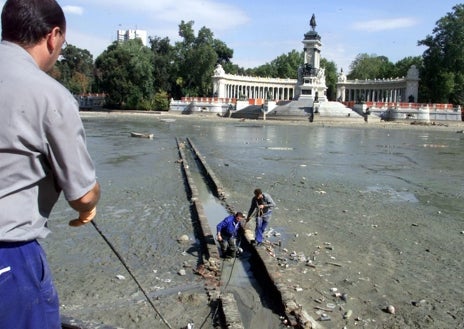Imagen secundaria 1 - Arriba, así estaba el suelo del estanque, aún con el lodo, tras vaciarse. Abajo, izq., un momento del vaciado; dcha, los biólogos tomando medidas a un pez
