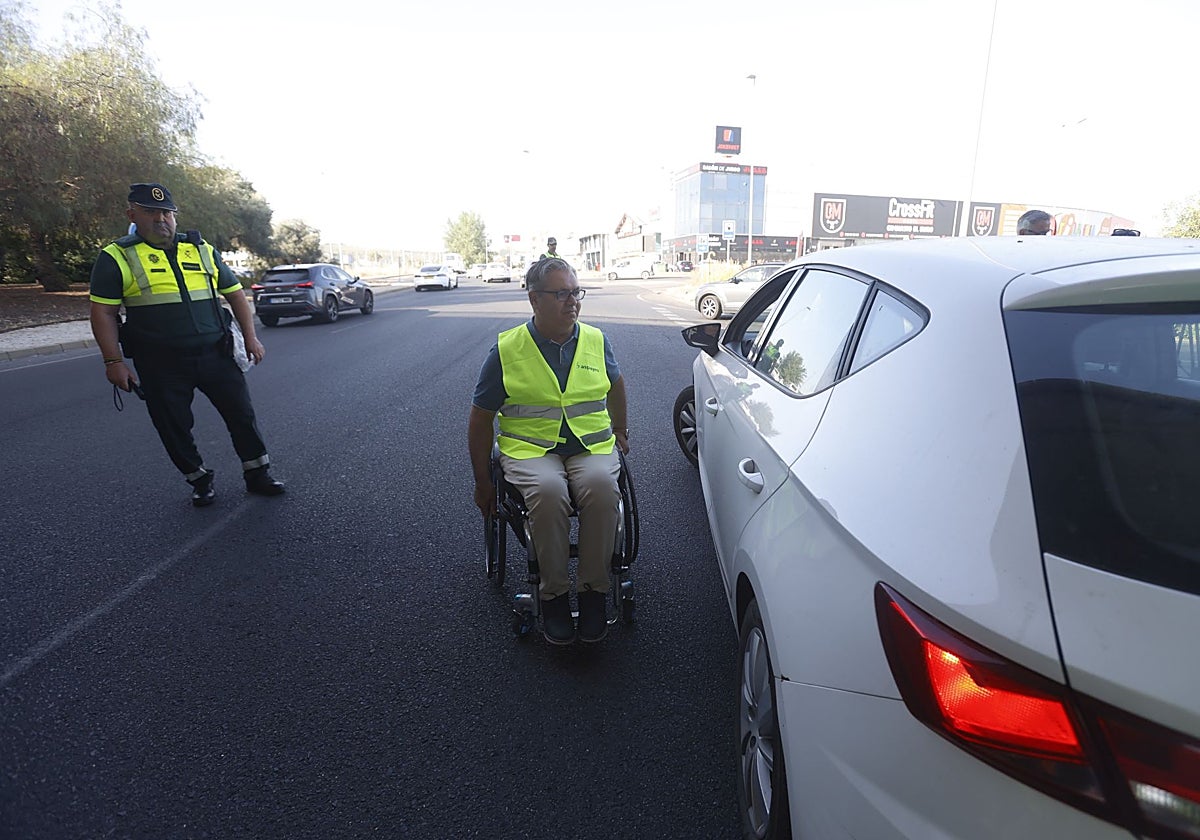 Una persona en silla de ruedas conversa con un conductor durante la campaña de la DGT