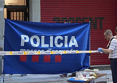 Imagen secundaria 1 - Arriba, agentes de la Científica localizan una vaina percutida ante el portal donde ha aparecido el cadáver de la víctima. Abajo, acordonando la zona, para la inspección ocular