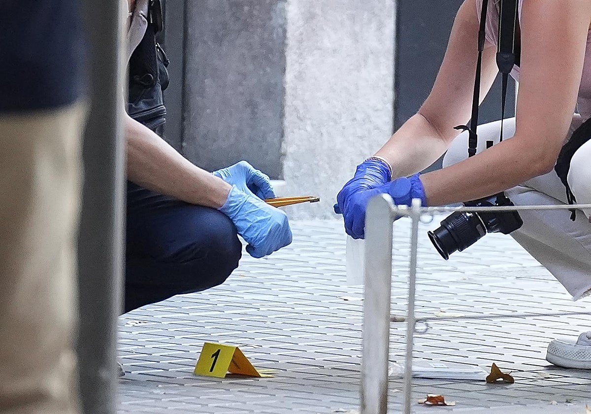 Agentes de la Científica recogen un proyectil tras la ejecución de un hombre en un portal del centro de Barcelona, este pasado martes
