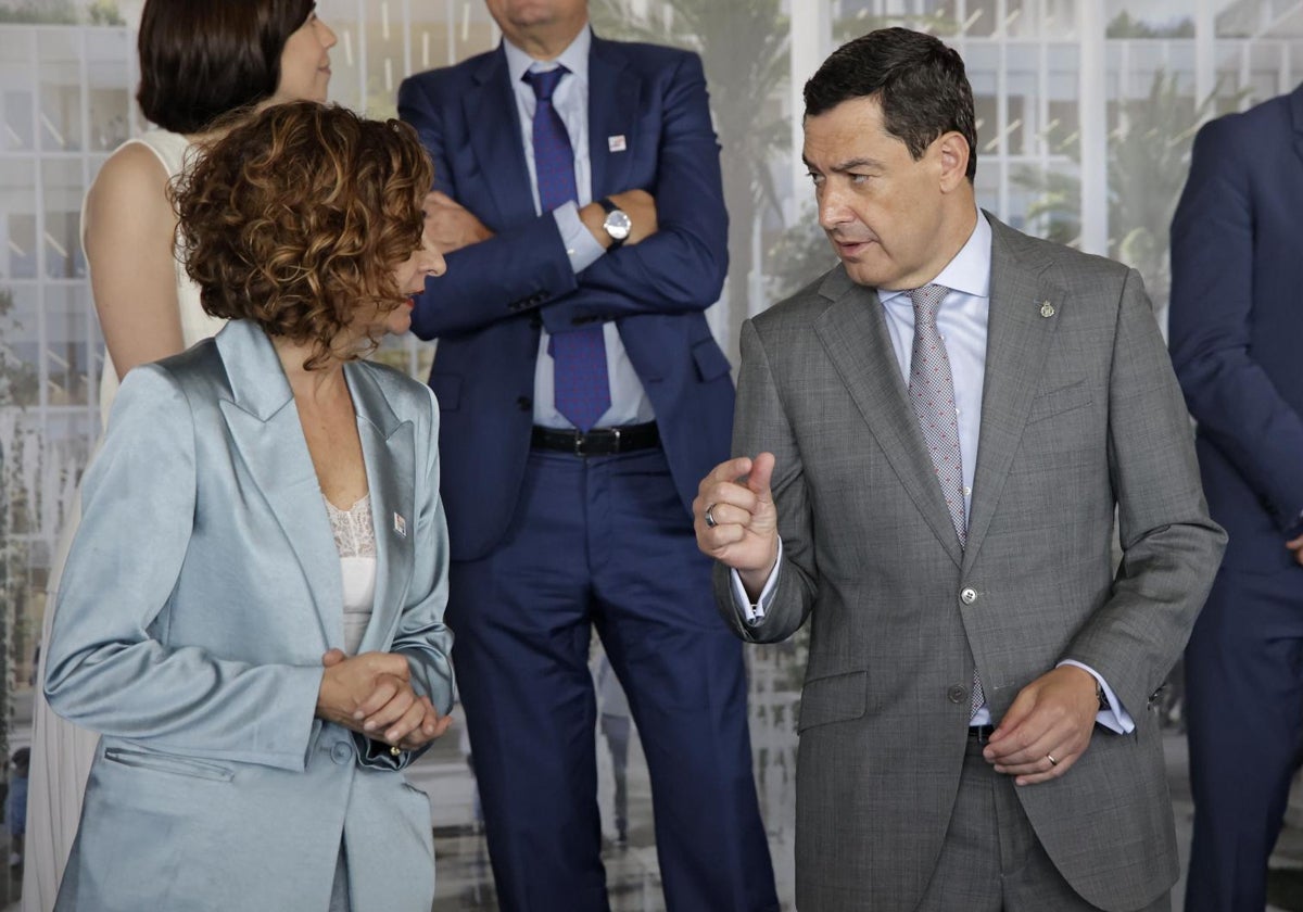 El presidente de la Junta de Andalucía, Juanma Moreno Bonilla, charla con la ministra de Hacienda, María Jesús Montero, en un acto en Sevilla el pasado mes de junio
