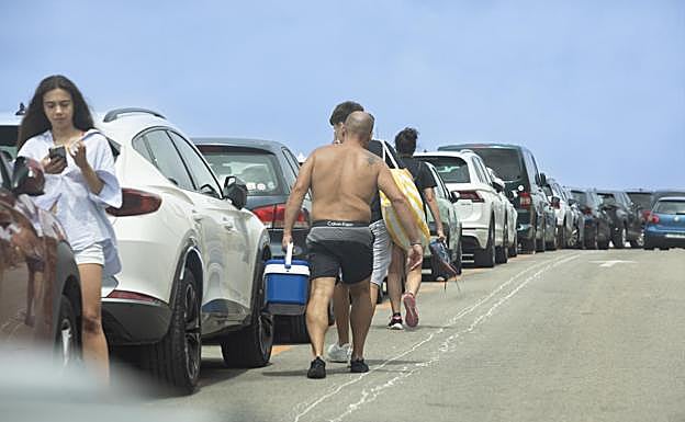 Turistas cargados con neveras y enseres para llegar a sus coches aparcados a kilómetros de la playa