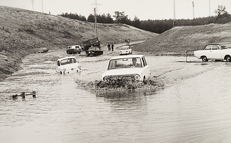 Imagen principal - Arriba, un vehiculo intenta atravesar un vado cubierto de agua. Abajo (izq.), el conductor se ve obligado a bajar y empujar el coche. Dcha., varios peatones intentando circular entre el barrizal