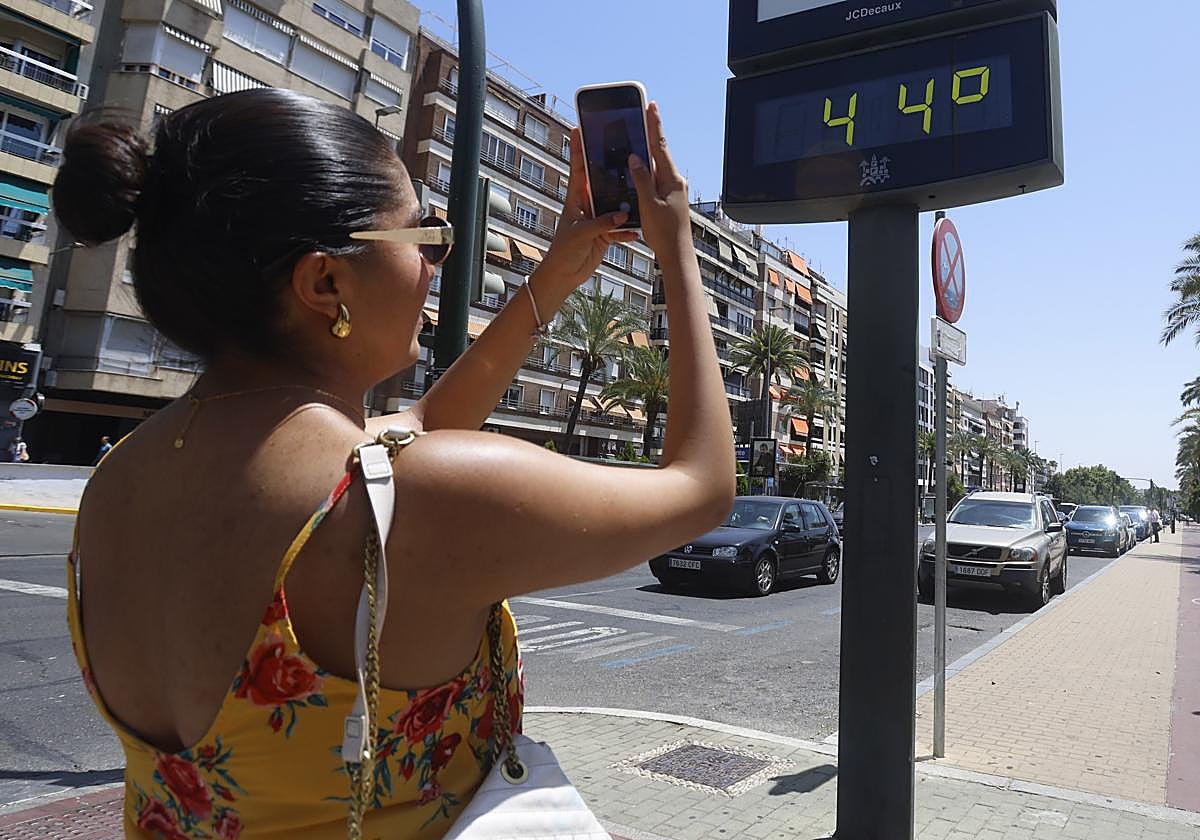 Una mujer fotografía un termómetro durante la larga ola de calor de agosto