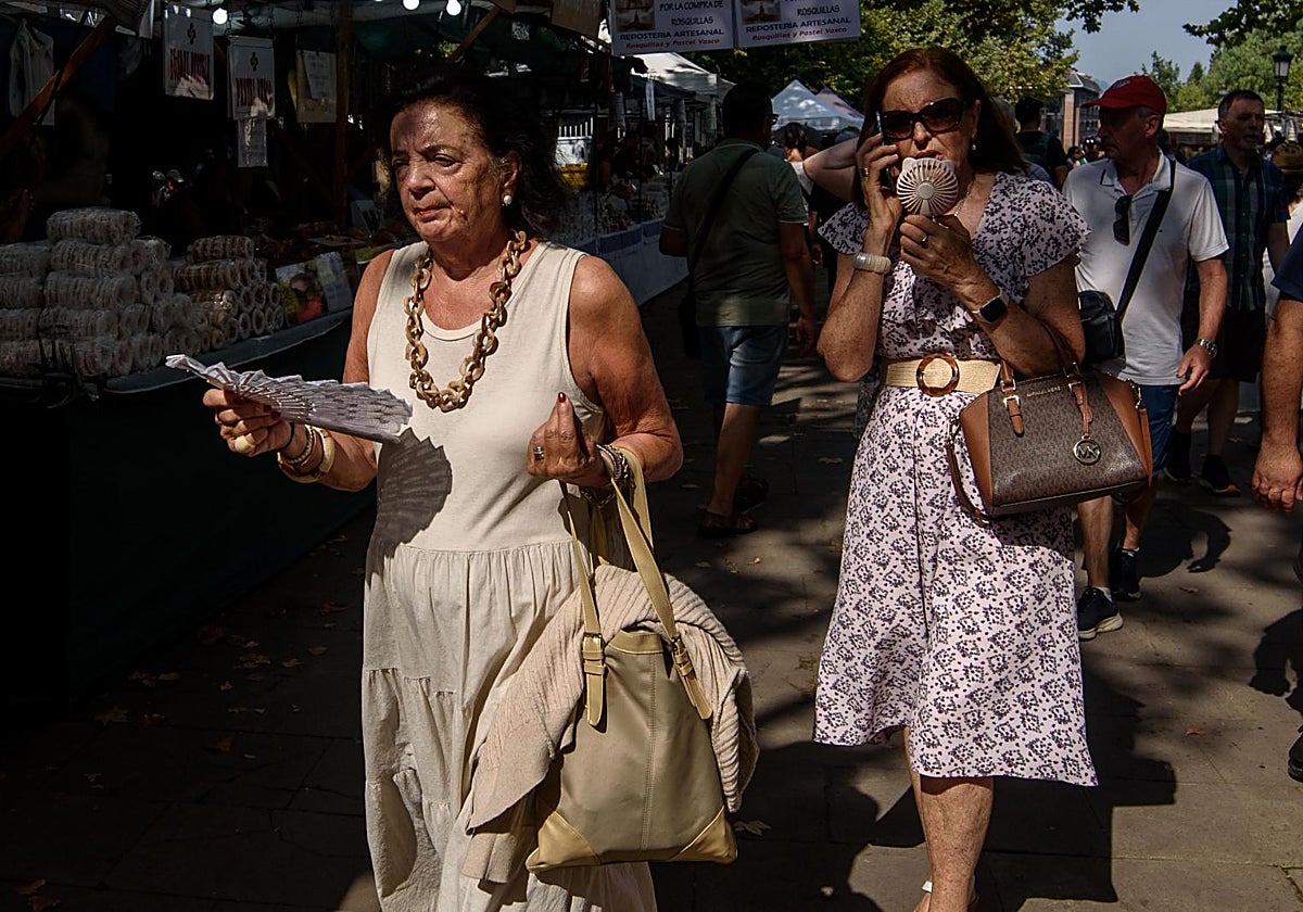 Dos mujeres hacen frente al calor con abanicos y un ventilador portátil durante el acto en la Basílica de Begoña en Bilbao