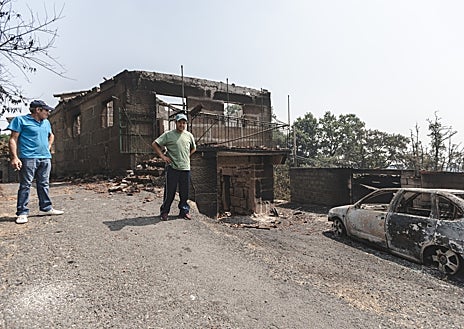Imagen secundaria 1 - Miguel Fernández contempla su explotación avícola devastada (arriba) / Samuel y José Antonio, frente a sus casas consumidas por las llamas (izq.) / Vecinos de Vilar de Lebres, escapan de las llamas junto a Agrícola Calvo (dcha.) 