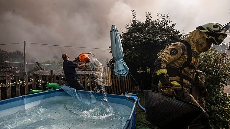 Vecinos y brigadistas arrojando agua al incendio de Carballeda de Avia