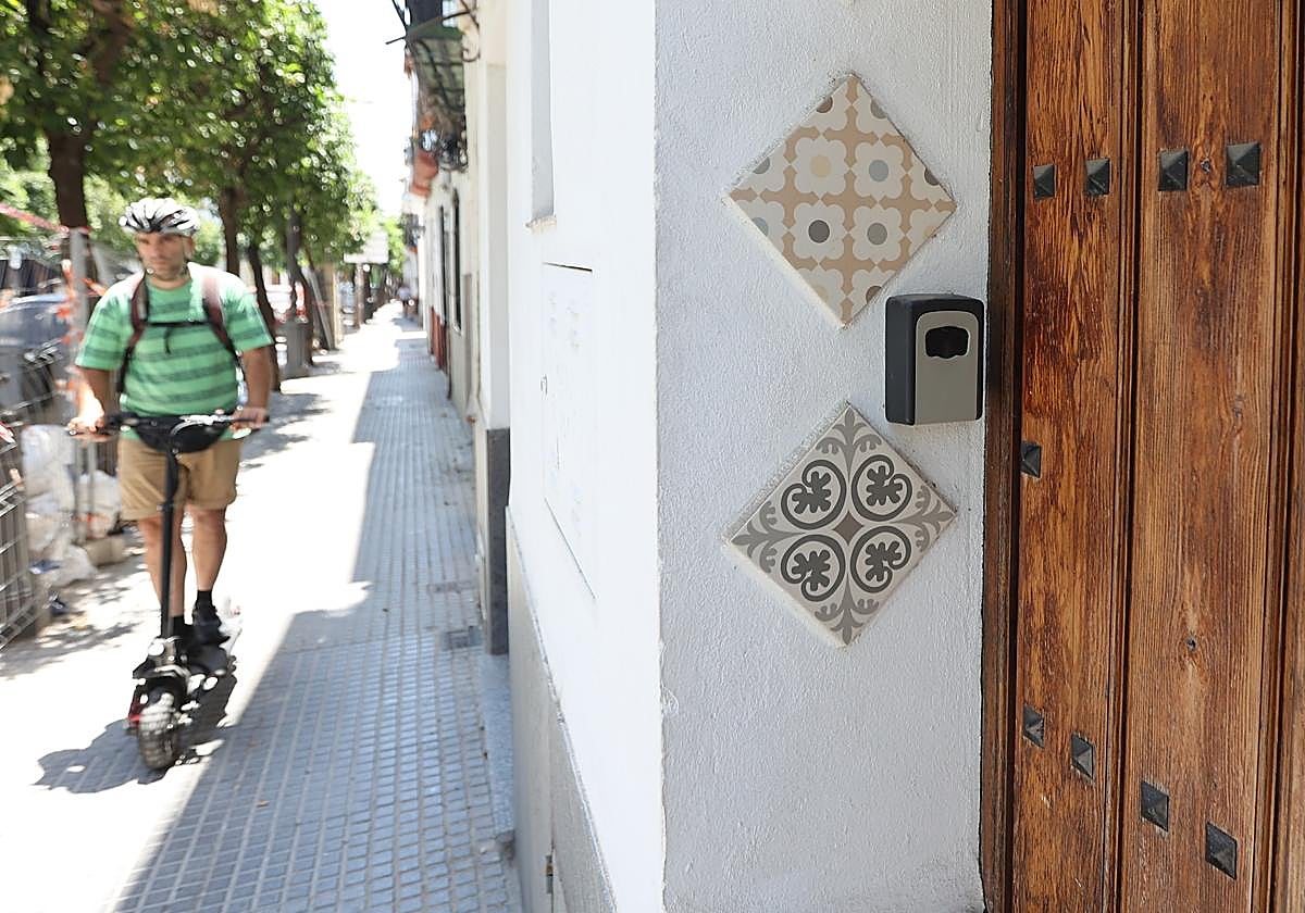 Un hombre pasa con un patinere delante de una vivienda turística en el Casco