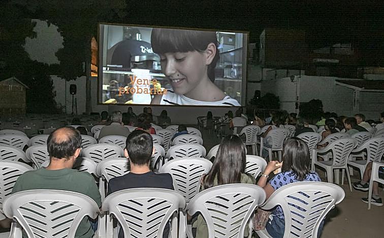 Imagen principal - Arriba, proyección en el Delicias; sobre estas líneas, varios espectadores toman unas consumisiones en el puesto del cine; a la derecha, la vendedora de las entradas. 