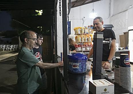 Imagen secundaria 1 - Arriba, proyección en el Delicias; sobre estas líneas, varios espectadores toman unas consumisiones en el puesto del cine; a la derecha, la vendedora de las entradas. 