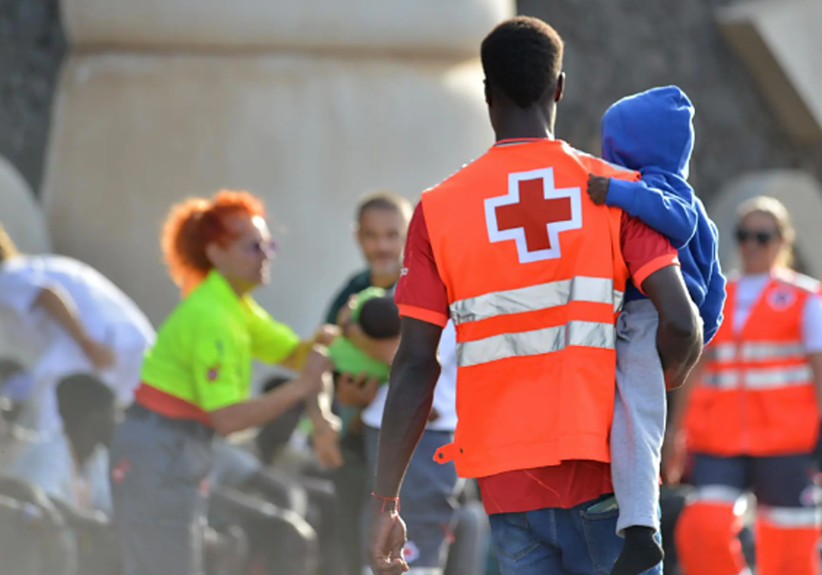 Un voluntario de Cruz Roja en El Hierro atiende a un niño llegado en cayuco al puerto de La Restinga, en una foto de octubre de 2023