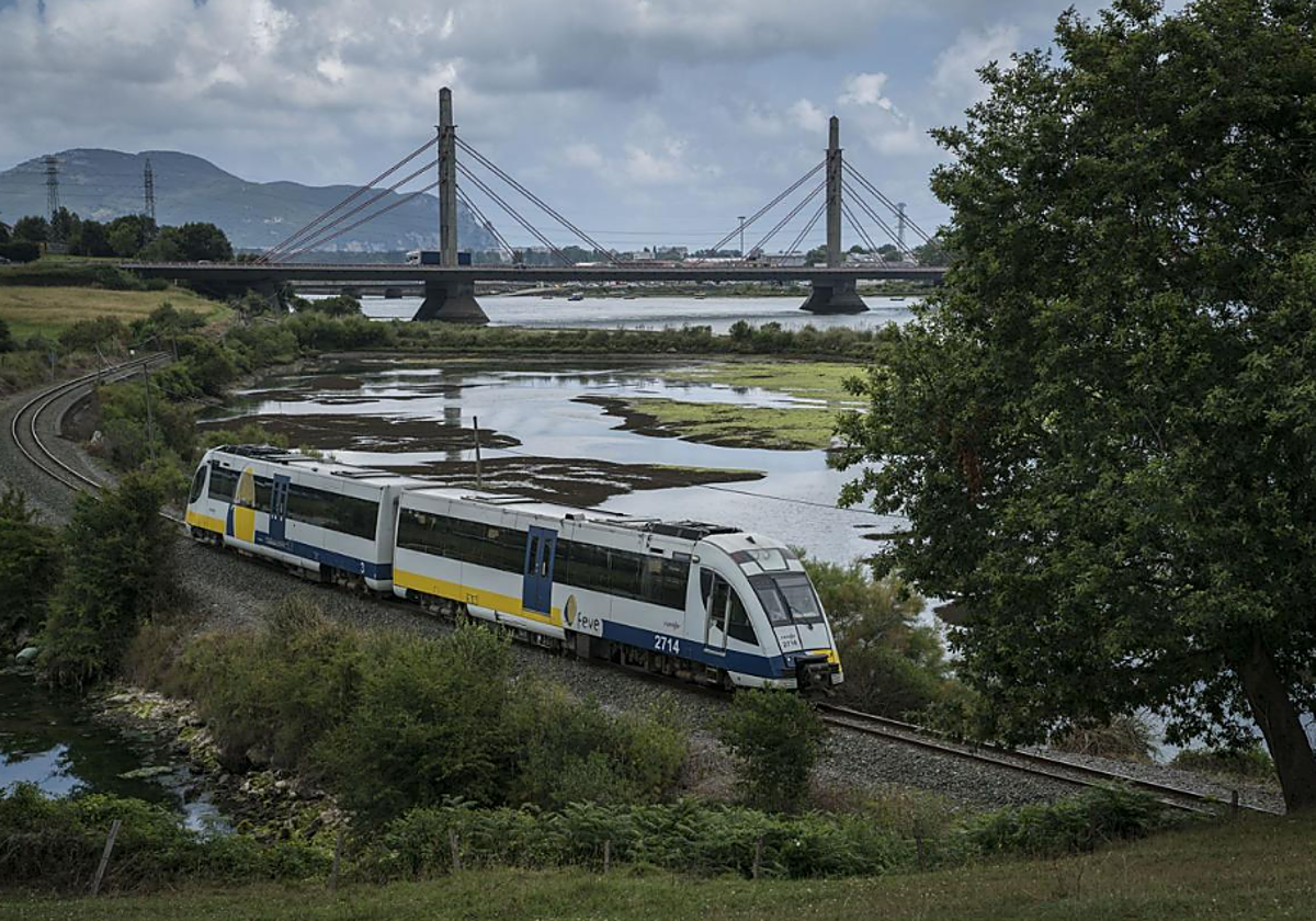 El tren camino de Santander, antes de pasar bajo el viaducto de Treto, en las marismas de Santoña y Joyel