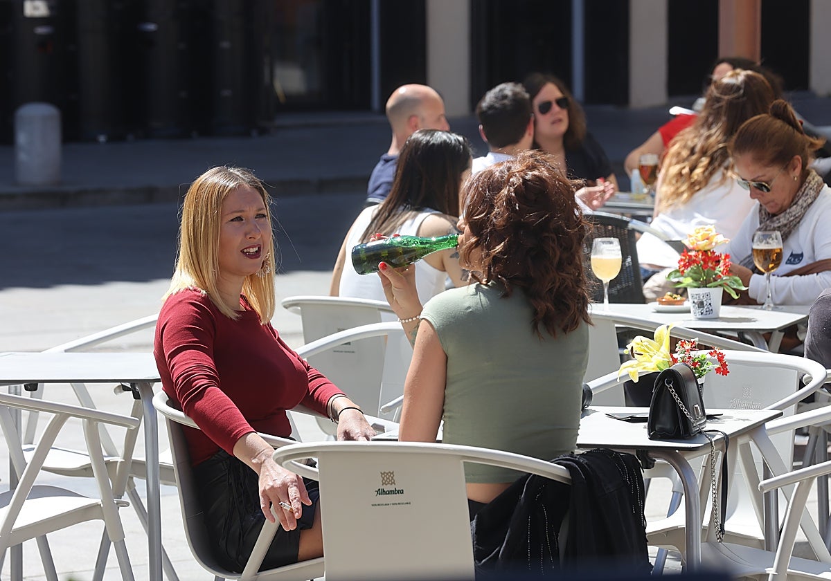 Una joven sostiene un cigarrillo mientras conversa con otra en el exterior de un bar