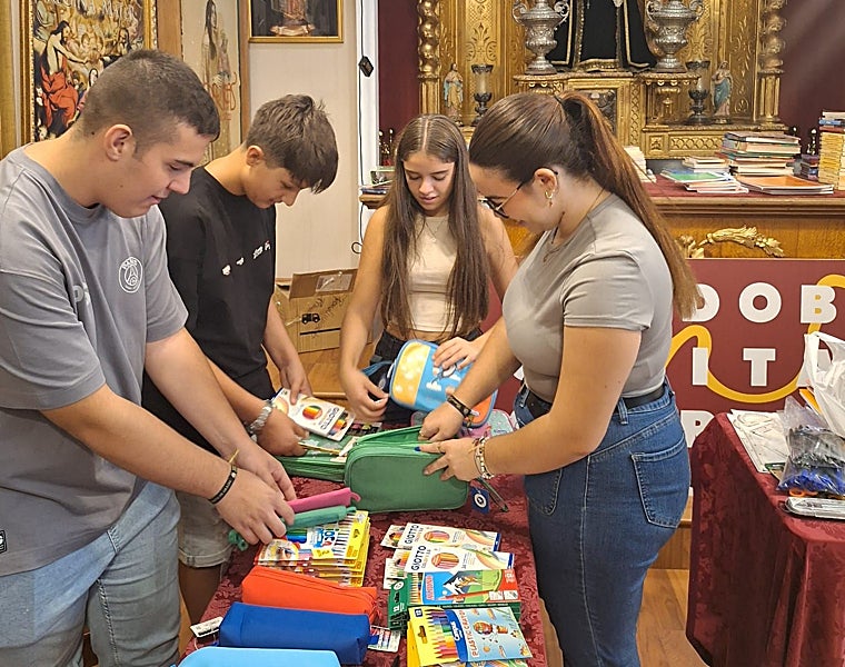 Jóvenes voluntarios ordenan el material escolar, en la sede de la Agrupación