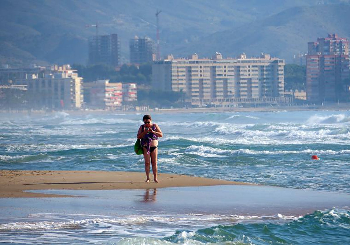 Una mujer pasea por la playa de Muchavista, en El Campello (Alicante)
