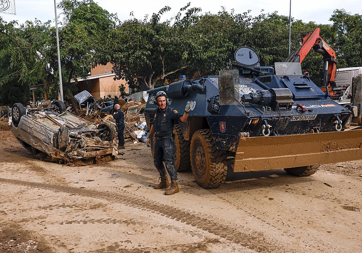 Efectivos de la Policía Nacional trabajan con vehículos especiales en el desescombro y retirada de coches arrasados por las riadas en Alfafar