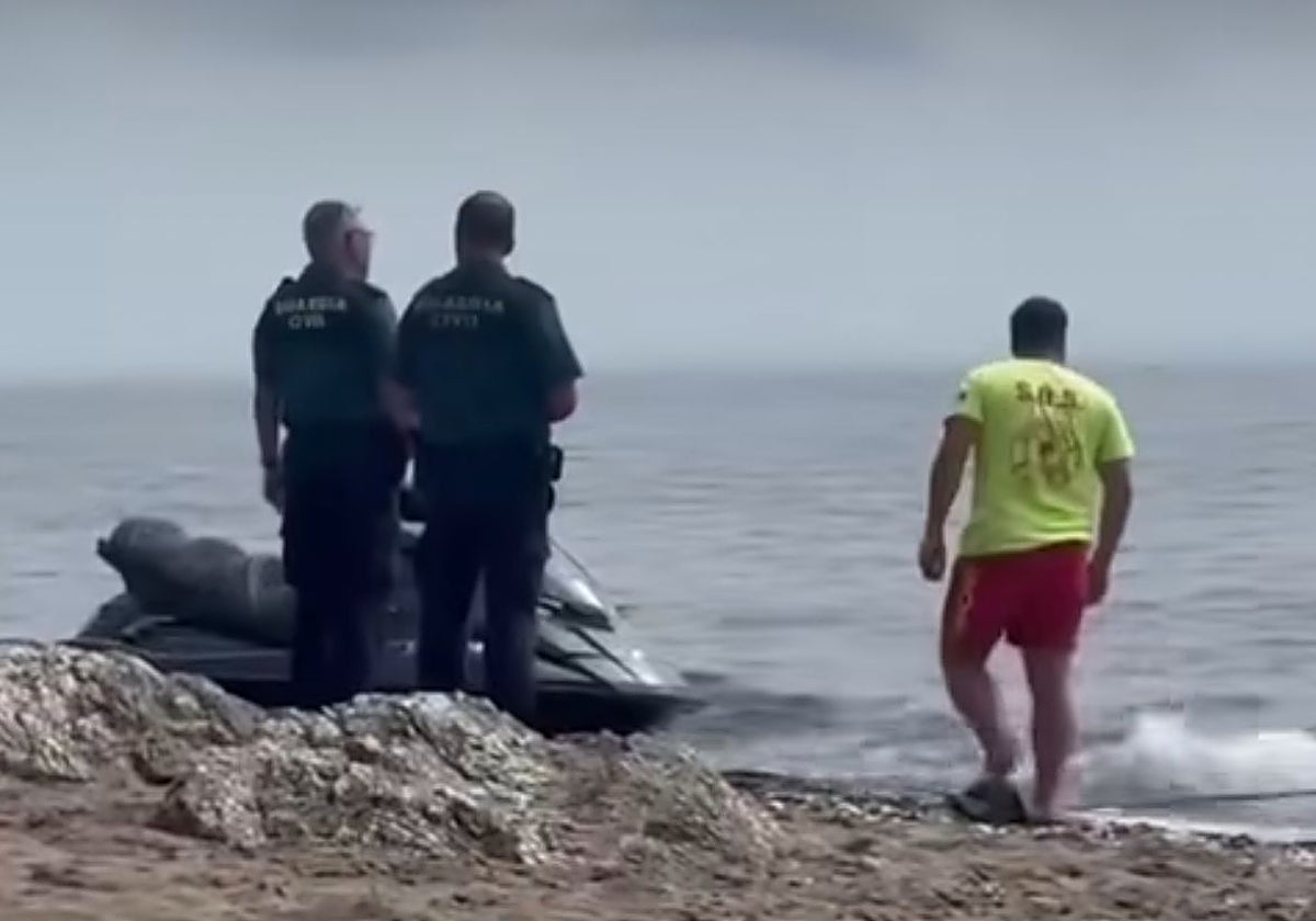Los agentes de la Guardia Civil junto a los servicios de socorrismo vigilan la moto que utilizaron para llegar