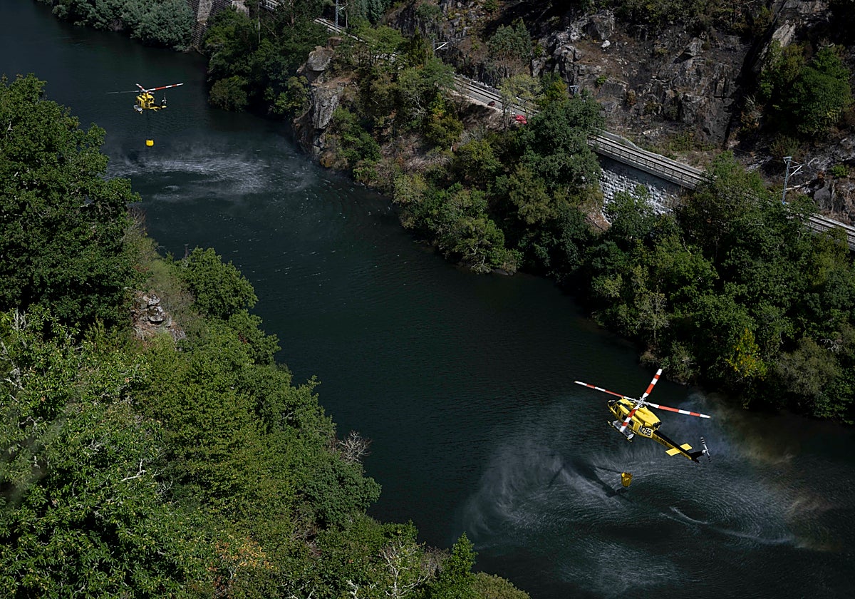 Dos helicópteros cargan agua en el río Sil para realizar labores de extinción en el incendio forestal de Pantón // EFE