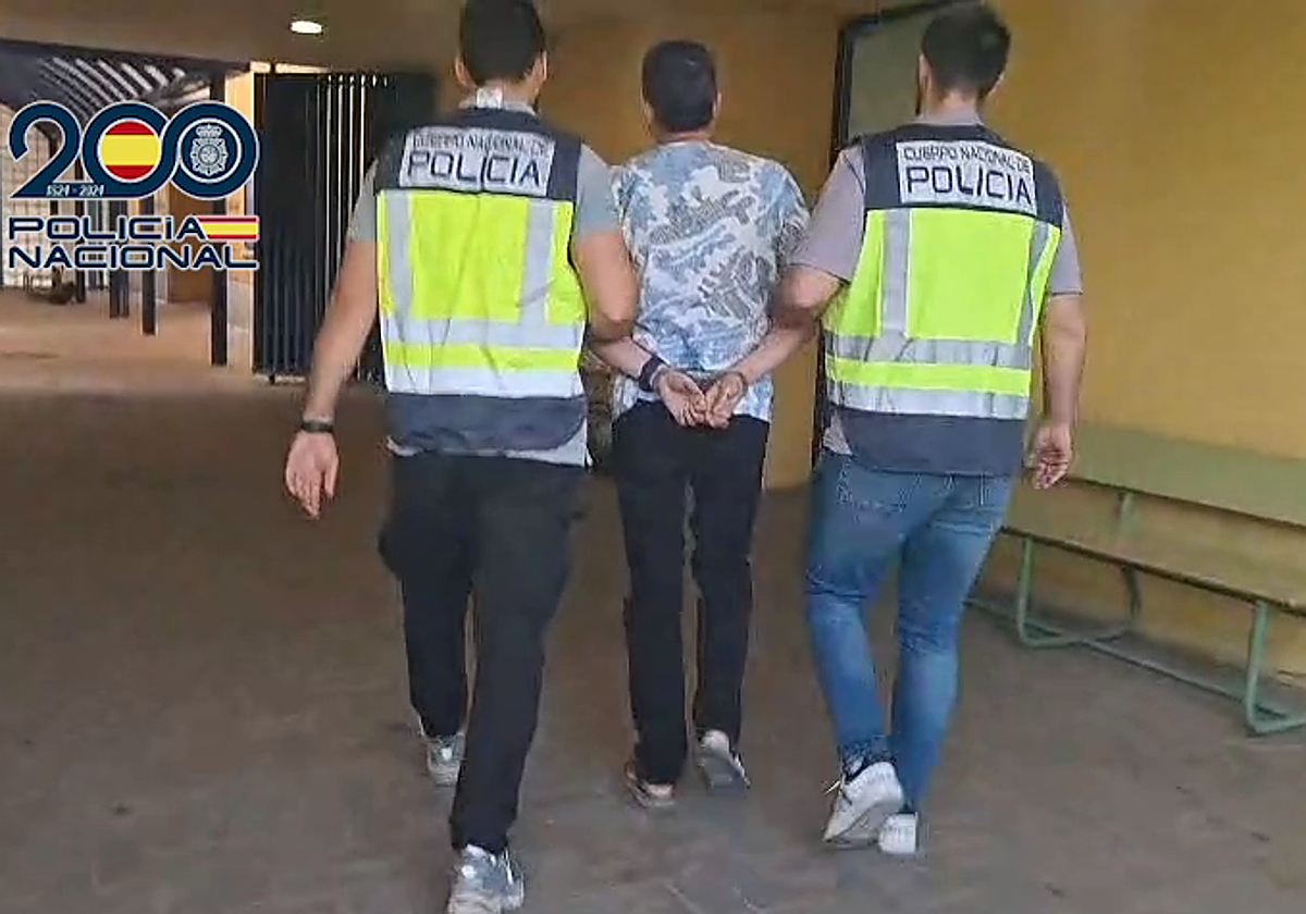 Dos agentes de la Policía Nacional con uno de los detenidos