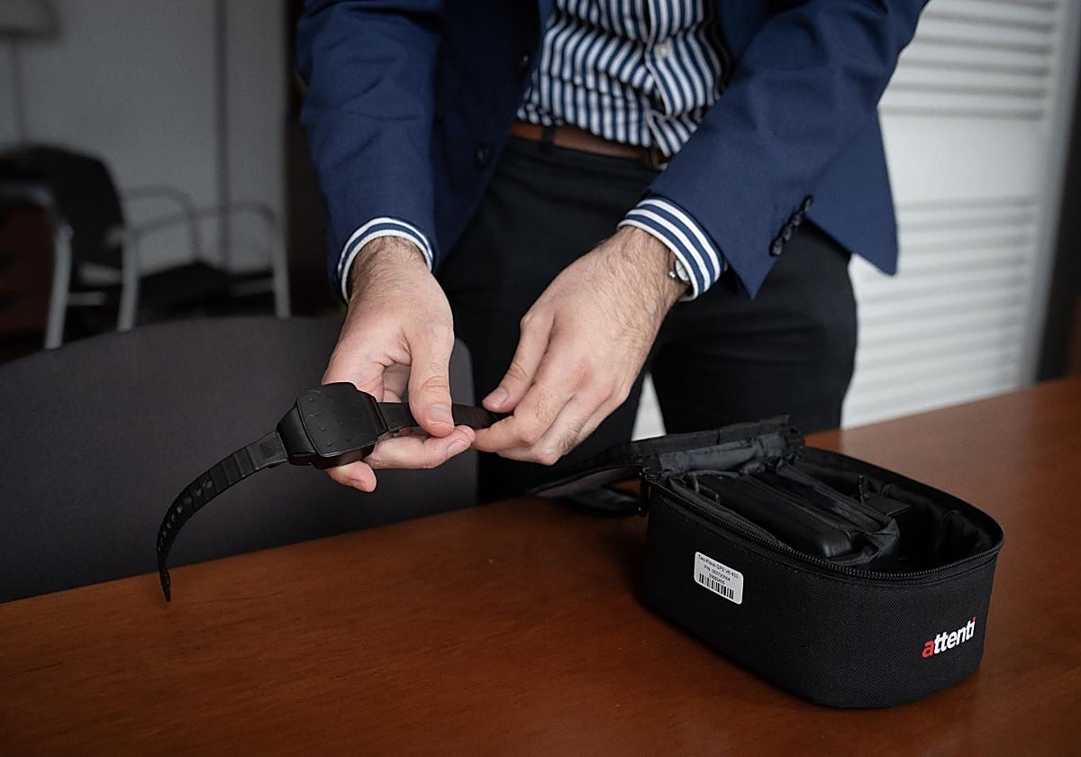 Una persona muestra una pulsera electrónica de geolocalización telemática