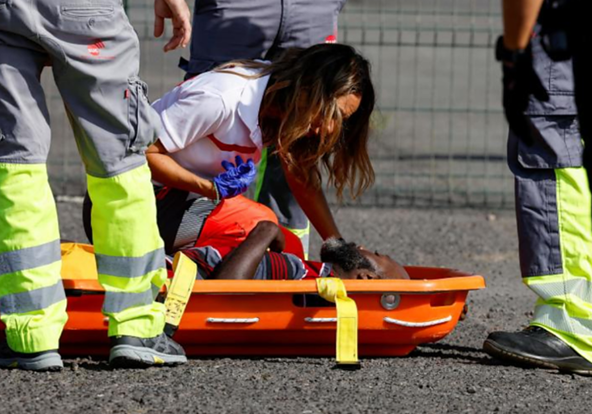 Una sanitaria atiende a uno de los migrantes rescatados e 2023 en el muelle de Arguineguín