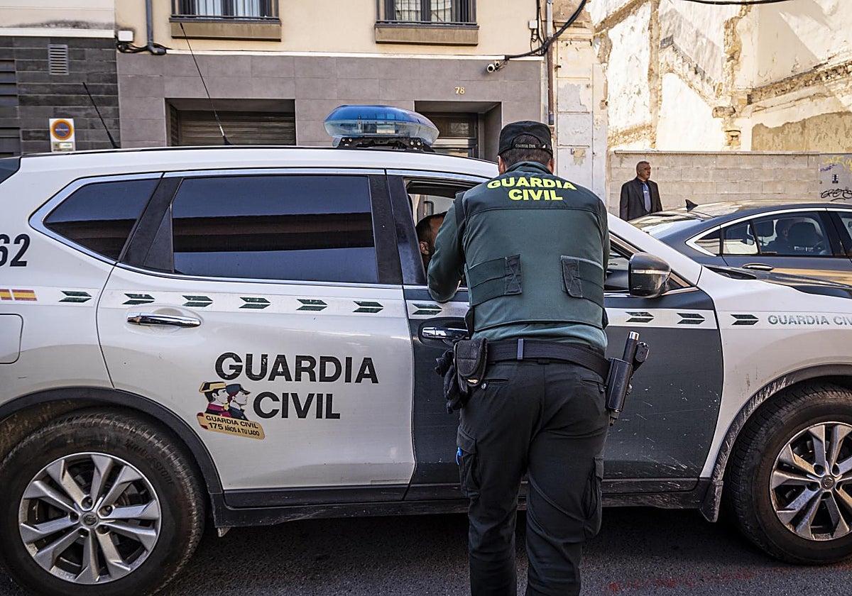 Un guardia civil junto a un vehículo patrulla