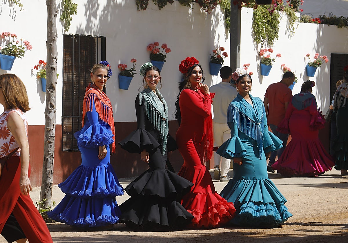 Mujeres vestidas de traje de gitana pasean por el Real de la Feria de Córdoba