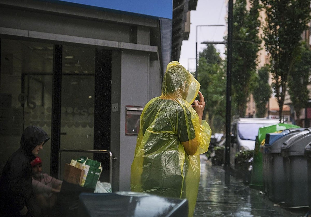 Una persona se protege de la intensa lluvia en Alicante
