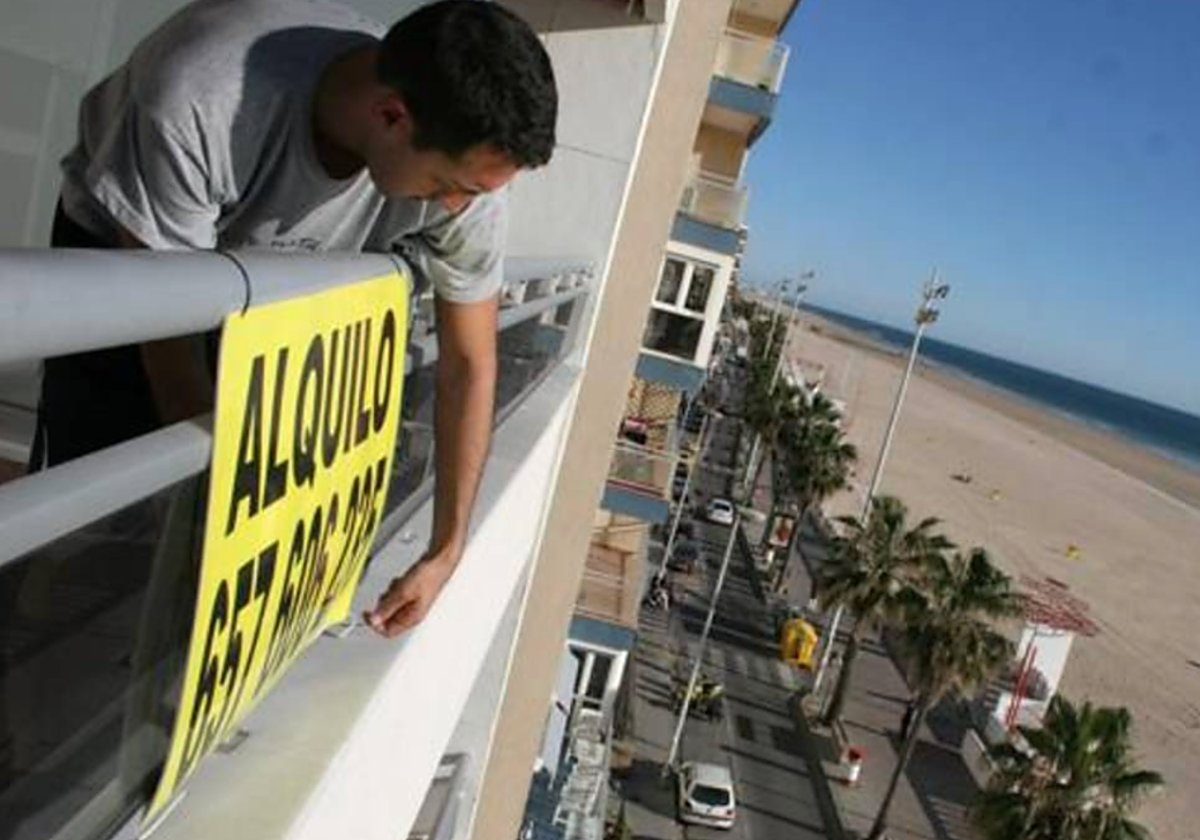 Un hombre coloca un cartel informando de vivienda en alquiler