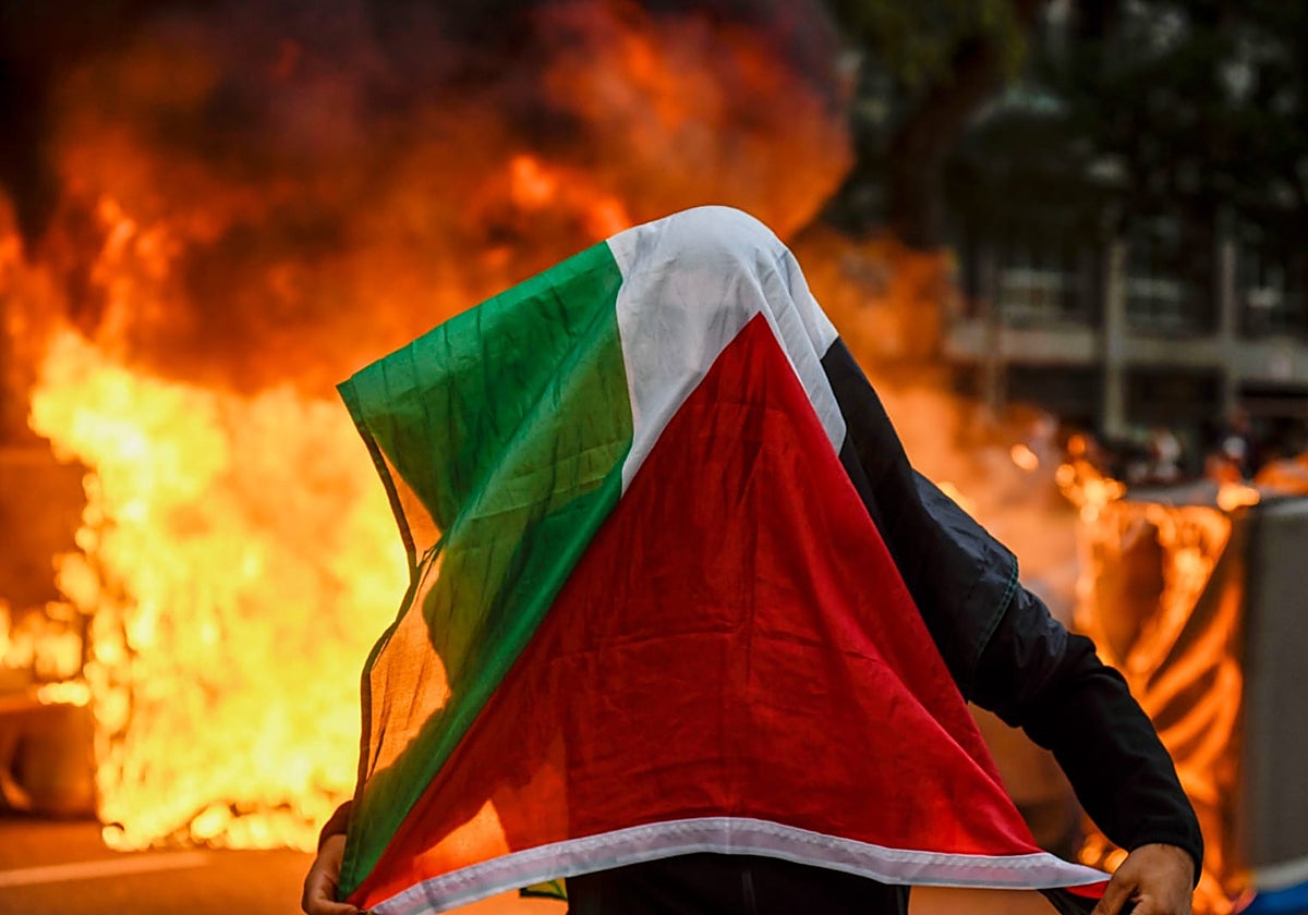 Uno de los manifestantes, esta tarde en Barcelona, ante los contenedores en llamas en la calle Tarragona