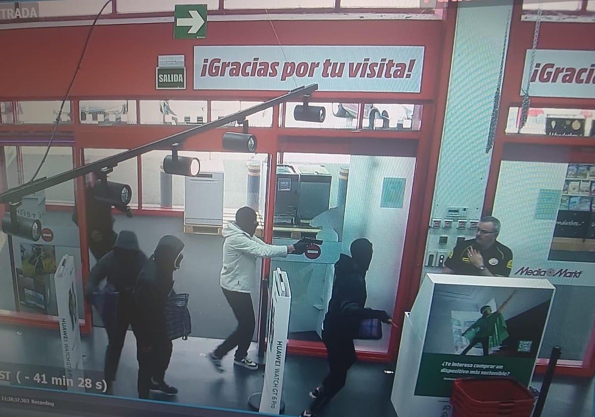 Los cinco atracadores entran en la tienda y encañonan al vigilante