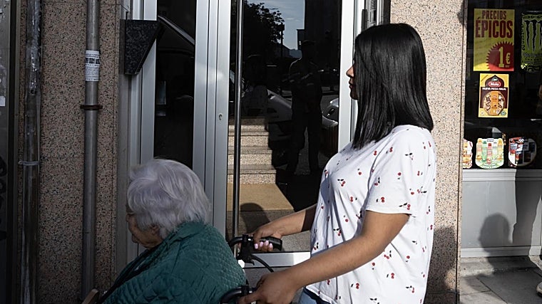 Una anciana en silla de ruedas pasa delante del portal de la avenida Monelos de La Coruña donde vivía la víctima