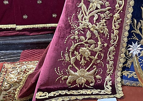 Imagen secundaria 1 - En la imagen superior, altar del triduo en honor de la Virgen del Desconsuelo. Debajo a la izquierda, detalle del manto de estreno. A la derecha, en primer plano la saya azul, con el Ave María 