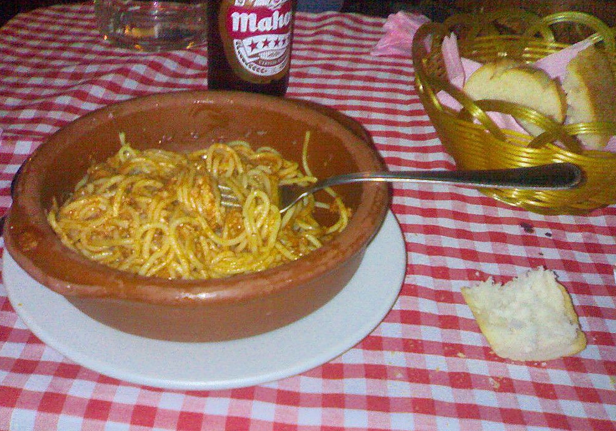 Un plato de espaguetis junto a una Mahou en Lady Pepa