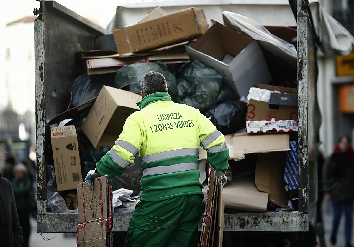 Un operario de la limpieza recoge cajas de cartón
