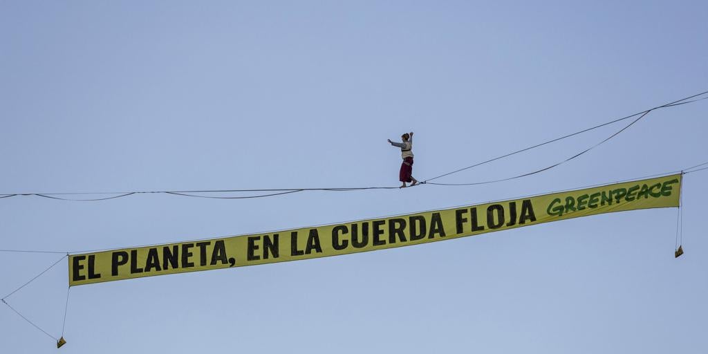Una funambulista camina entre dos edificios en la plaza de España de Madrid para protestar contra la crisis climática