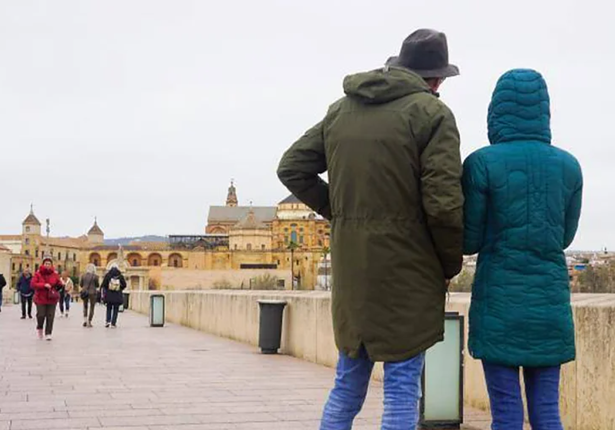 Gente caminando abrigada por el Puente Romano de Córdoba, durante una jornada de frío