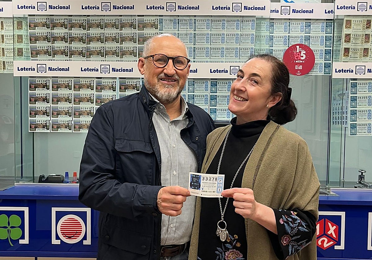 Mercedes Domínguez, propietaria de la administración, con su marido y uno de los décimos de 33.278