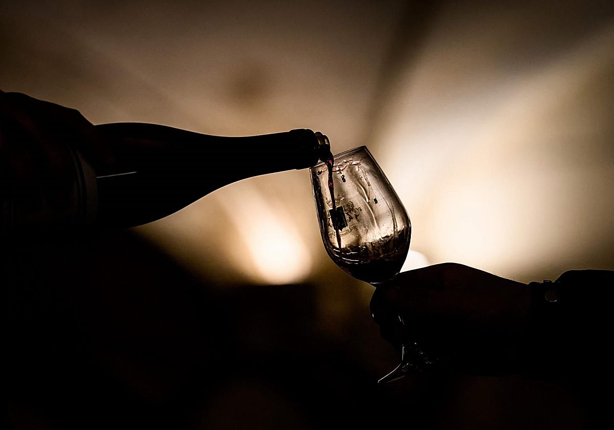 Una persona se sirve una copa de vino