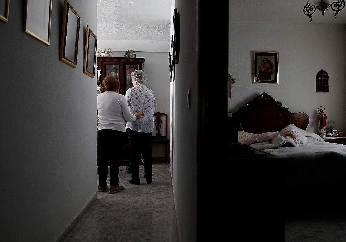 Una mujer en su casa es ayudada por un familiar en materia de dependencia