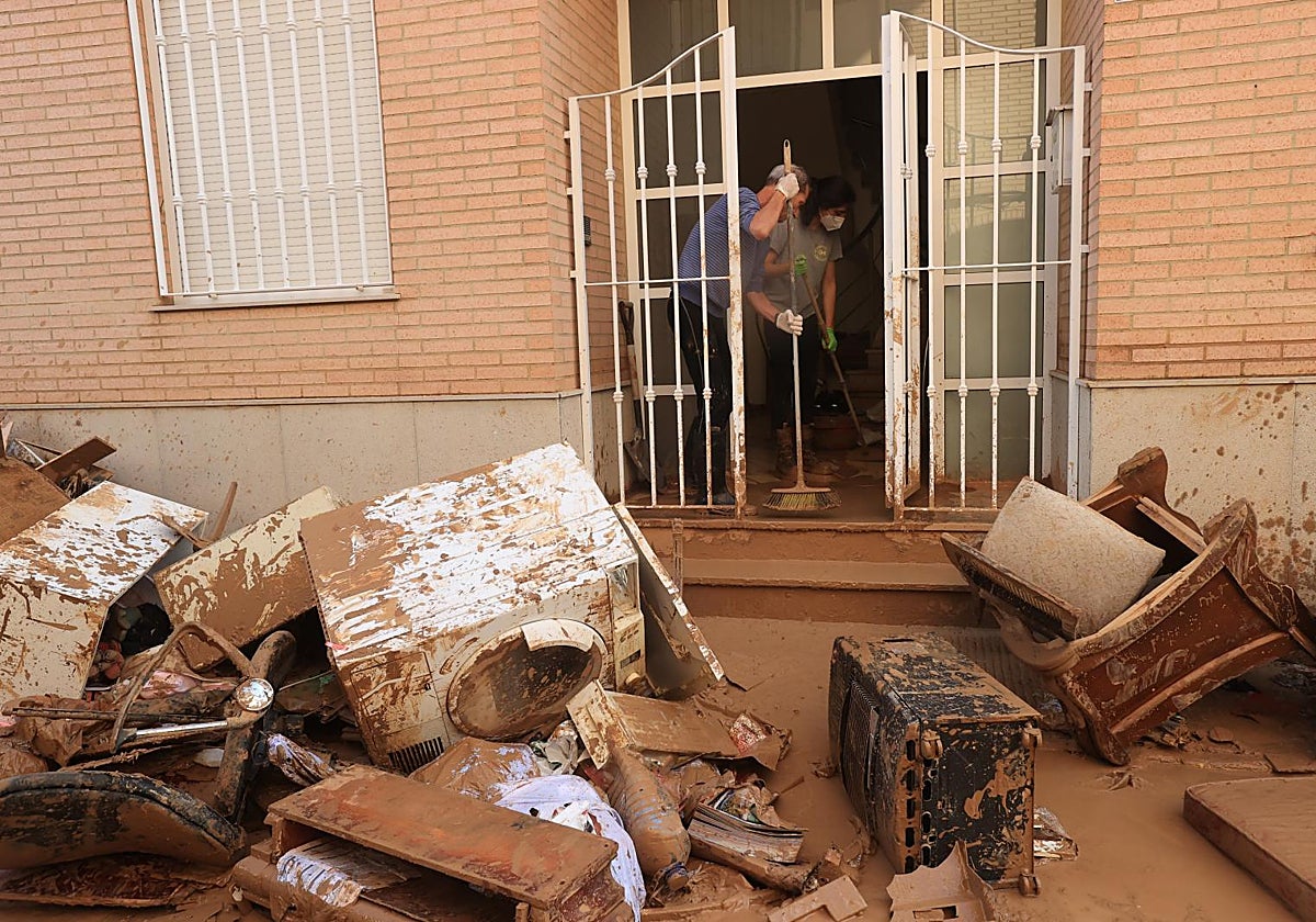 Vecinos de Catarroja (Valencia) limpian de barro una vivienda inundada por la riada de la dana