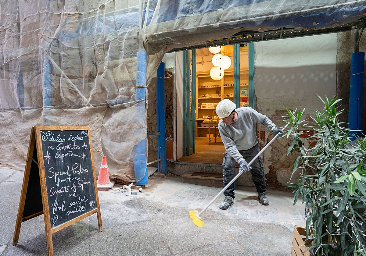 Un obrero limpia junto al andamio situado en la puerta de El Jardín del Convento por las obras del monasterio