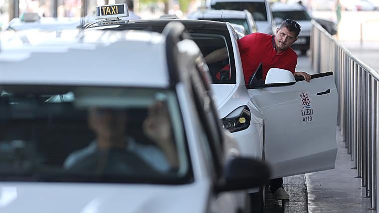 A taxi driver gets out of his car at the train station stop