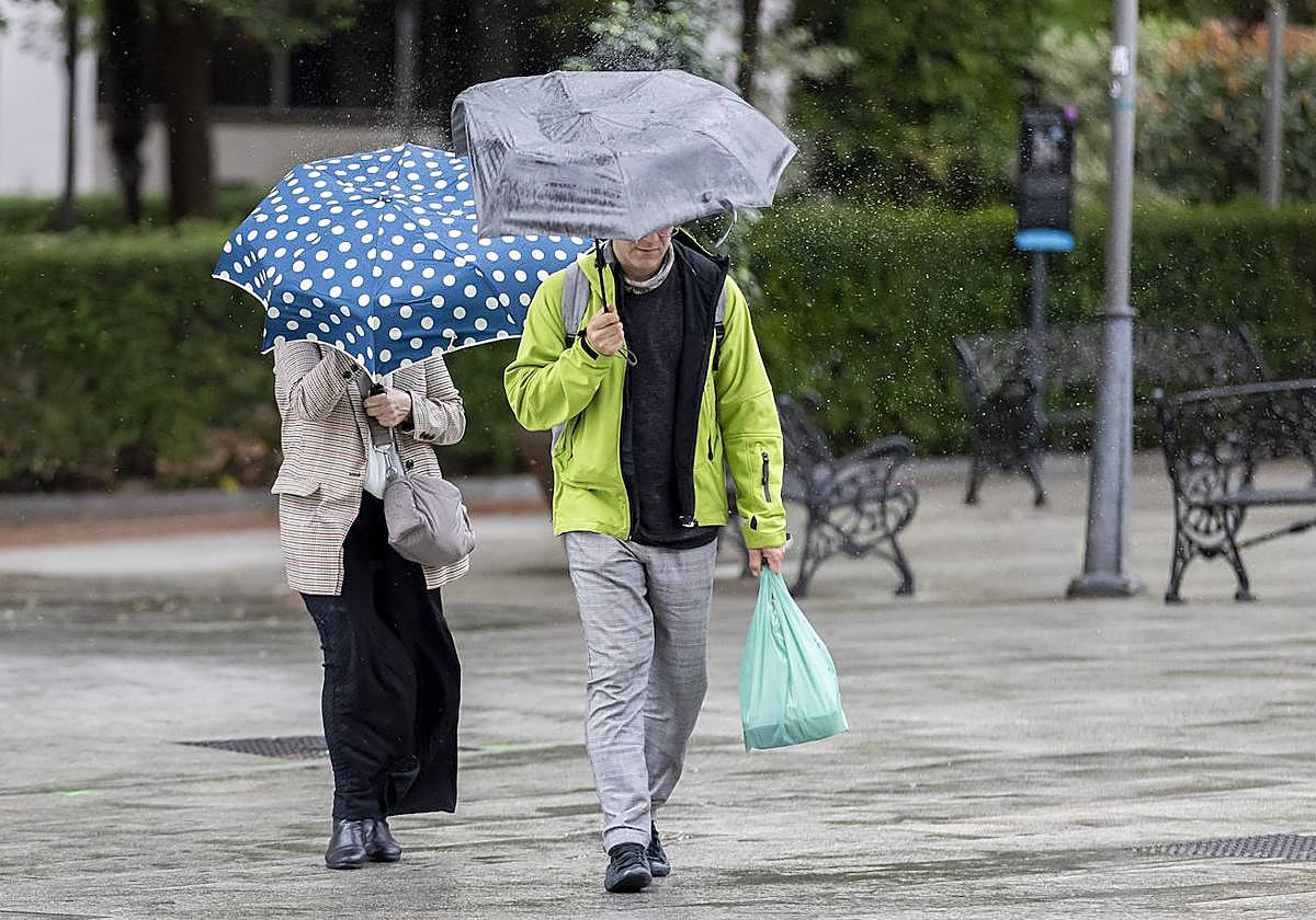Several people protect themselves with an umbrella from the rain and wind in Huelva, where AEMET has activated the yellow warning in the province of Huelva