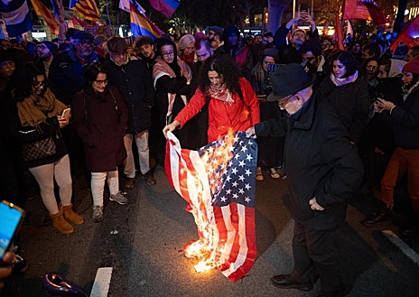 Imagem secundária 1: Acima, uma mulher comemora a tomada de poder de Maduro agitando a bandeira venezuelana no Arco do Triunfo, em Barcelona. Com este espírito, proteste contra a operação dos EUA a partir da Praça Urkinaon.