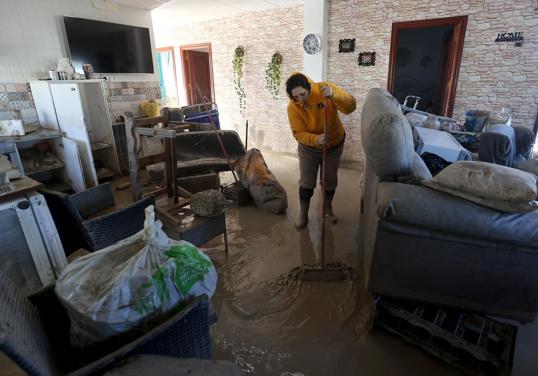 Una afectada por las inundaciones limpia su vivienda de barro y agua