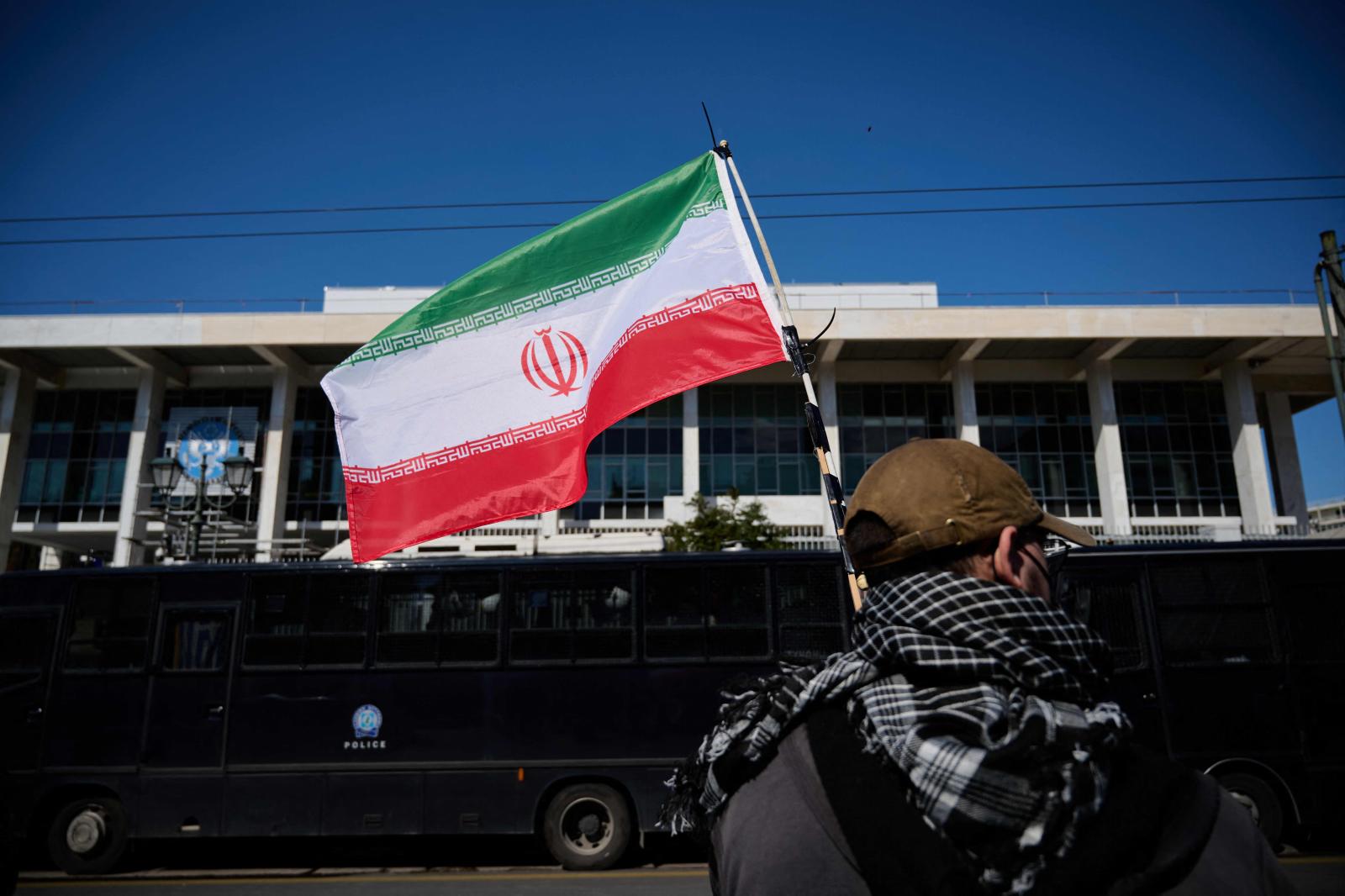 Un manifestante sostiene una bandera iraní durante una protesta contra el ataque de Estados Unidos e Israel.